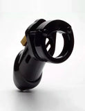 The CB-6000 Male Chastity Device in black is shown against a blank background. The chastity cage is the shape of a flaccid penis and is black and shiny, with a brass padlock on top. There is a rectangular slit at the tip of the cage.