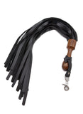 The Sissoo Rosewood Short Round Handle Leather Flogger is shown on a white background. Attached to the flogger is the included leather hanger strap with crab-claw hook. The BDSM impact play toy features leather falls and a wooden round handle.