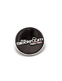 The Stockroom Enamel Pin is shown against a blank background. The pin is circular and has a black background with The Stockroom logo on it and the slogan “Think Kink” underneath.