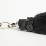 close up of the attachment of a faux fur foxtail finger flogger against a white background. 