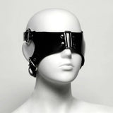 Black rubber blindfold on a white mannequin head against a white background shot at an angle. 