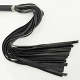 A black flogger with long, 26" rubber falls lies on a white background, arranged in an S shape. 