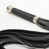 Close-up of the Lumina Long Flogger's handle, showing the thin black cord wrapped around the shaft and the stainless steel base.