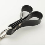 Close up of black rubber loops with a metal ring on a white background