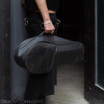 A person from the waist down, carrying the Shredder machine in a black bag, about to enter a door. 