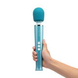 A person's hand holds a Le Wand vibrator upright against a white background.