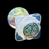 A transparent PVC butt plug shown from the base. The bottom of the plug has a glittery, bejeweled texture. 