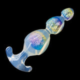 An anal bead toy made of transparent PVC on a black background. The surface has an iridescent sheen, and the inside contains sparkly yellow, purple, and blue particles. 