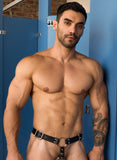 A close-up of a is shown. He is wearing the Anal Plug Harness For Men. the black leather straps buckle at the hips and are attached to an O-ring on his pelvis. There is another metal O-ring around his cock and balls.