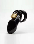 The CB-6000 Male Chastity Device in black is shown against a blank background. The chastity cage is the shape of a flaccid penis and is black and shiny, with a brass padlock on top. There is a rectangular slit at the tip of the cage.