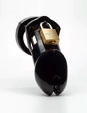 The CB-6000 Male Chastity Device in black is shown against a blank background. The chastity cage is the shape of a flaccid penis and is black and shiny, with a brass padlock on top. There is a rectangular slit at the tip of the cage.